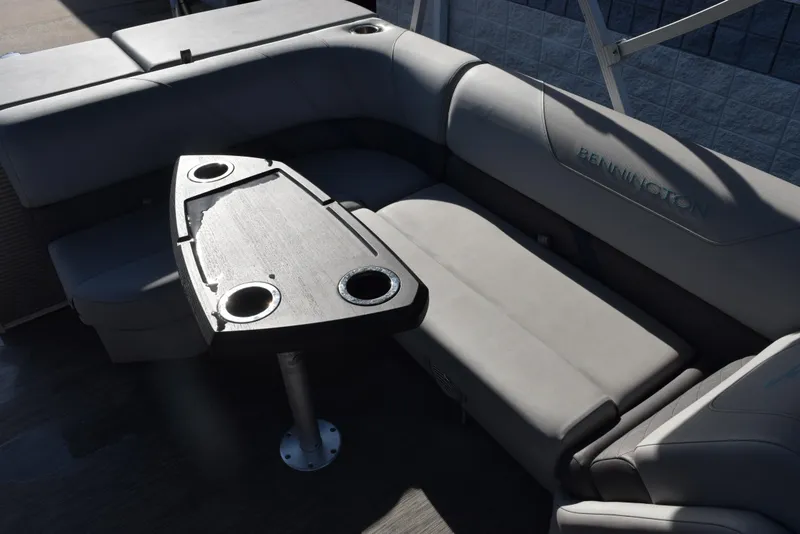Slide: The Image of 2021 Bennington 18 SLX boat interior with gray seating and a table with cup holders. - 11