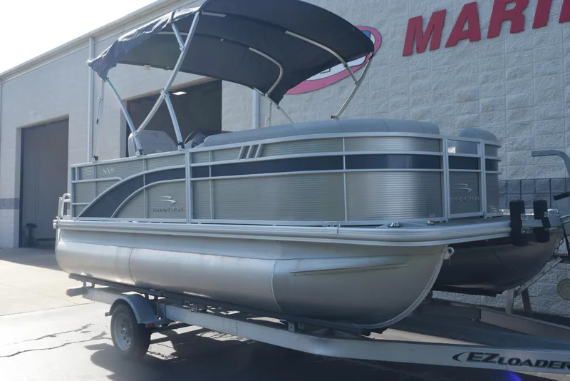 Slide: The Image of 2021 Bennington 18 SLX pontoon boat on trailer outside a marine dealership. - 2