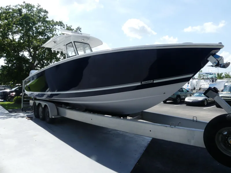 Slide: The Image of 2026 Jupiter 340LS boat on trailer, parked outdoors under clear sky. - 10