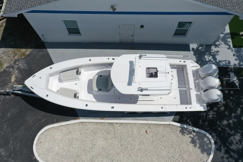 Slide: The Image of Aerial view of 2026 Jupiter 340LS boat with triple engines, parked beside a building. - 2
