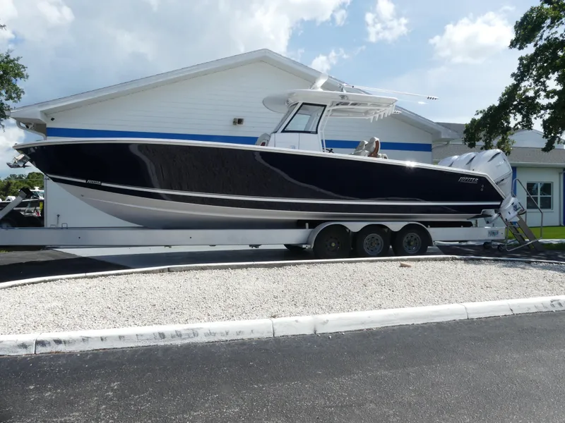 Slide: The Image of 2026 Jupiter 340LS boat on trailer, parked outside a building under a cloudy sky. - 5
