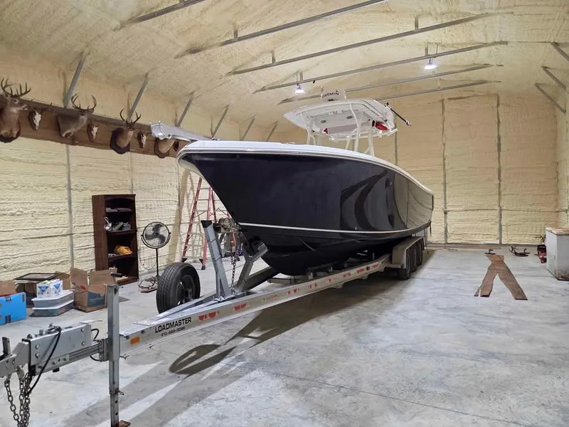 Slide: The Image of 2013 Sailfish 290 CC boat on trailer in spacious indoor storage. - 10