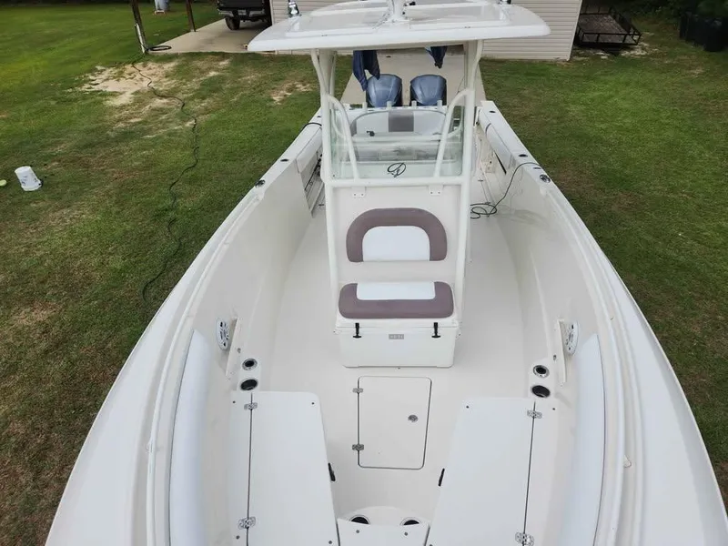 Slide: The Image of 2013 Sailfish 290 CC boat with spacious deck and seating, parked on grass. - 16
