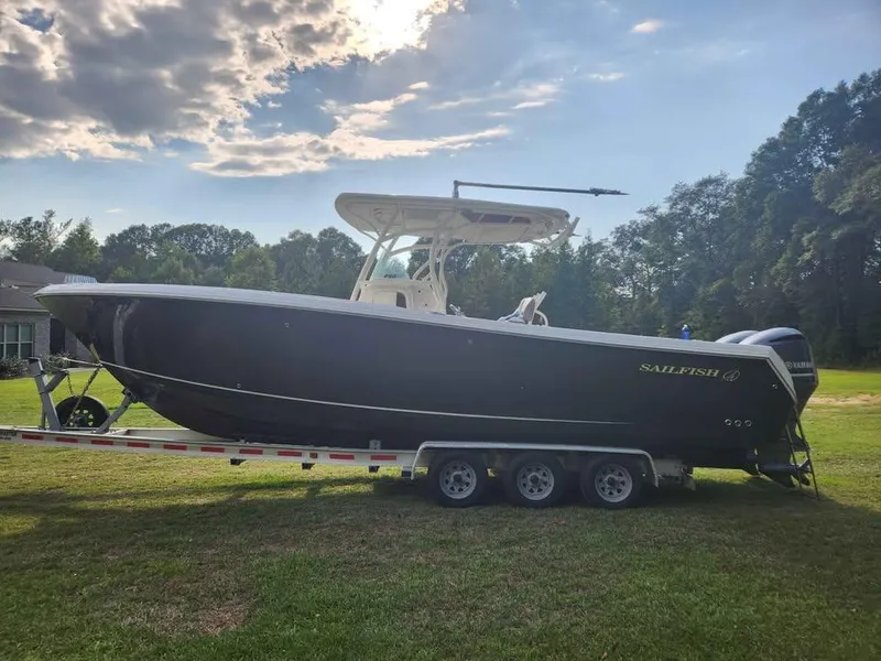 The Image of 2013 Sailfish 290 CC boat on trailer, parked on grass under cloudy sky. - 4