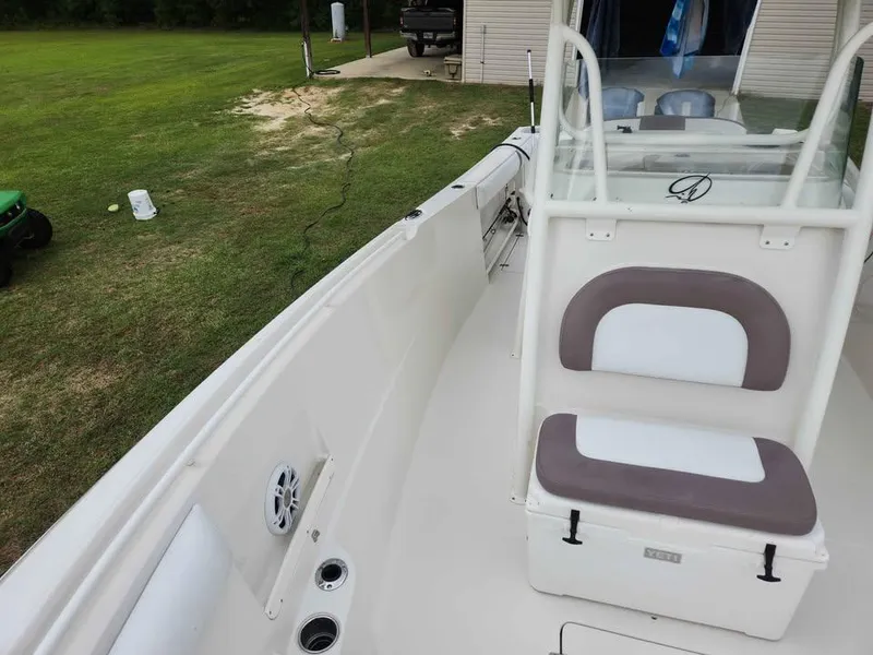 Slide: The Image of 2013 Sailfish 290 CC boat interior with seating and console, parked on grass. - 7