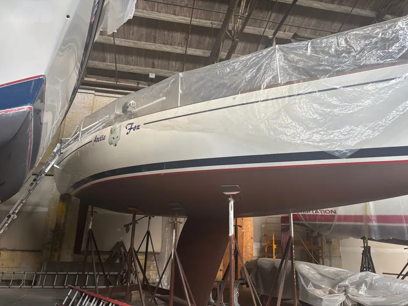 Slide: The Image of 1987 Holby Tripp sailboat "Arctic Fox" in a warehouse, covered and elevated on stands. - 2