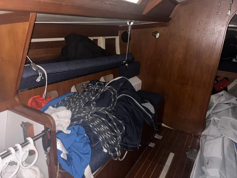 Slide: The Image of Interior of a 1987 Holby Tripp sailboat with ropes and gear on wooden benches. - 43