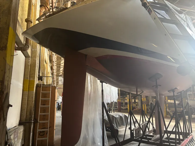 Slide: The Image of 1987 Holby Tripp sailboat in a workshop, supported by stands, under maintenance. - 5