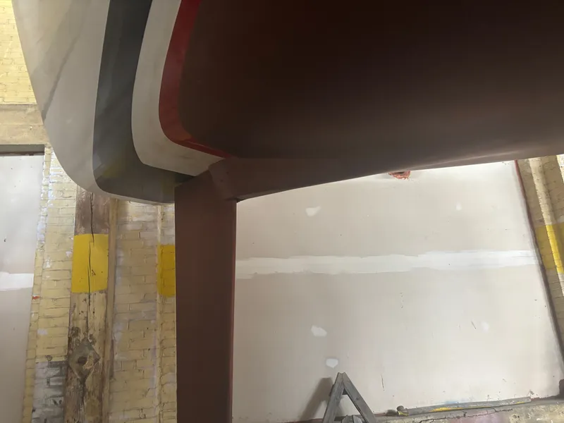 Slide: The Image of 1987 Holby Tripp boat hull in a workshop setting, showing keel and rudder. - 7