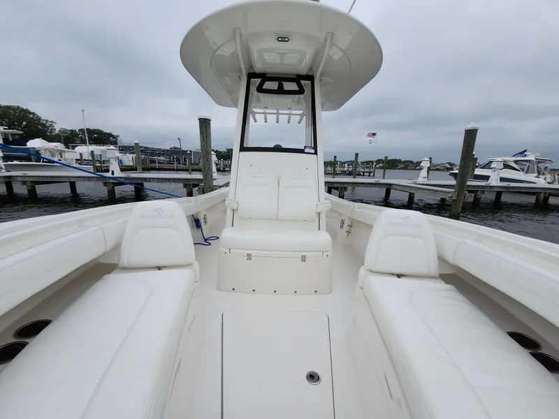Slide: The Image of 2021 Regulator 25 boat interior at marina, featuring white seating and console. - 13