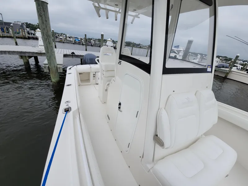 Slide: The Image of 2021 Regulator 25 boat docked at marina, featuring sleek white interior and seating. - 18