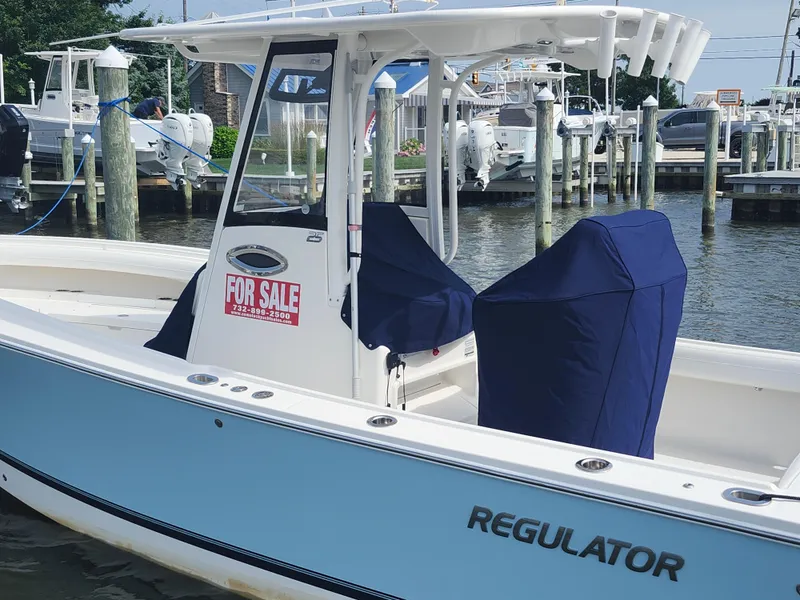 Slide: The Image of 2021 Regulator 25 boat for sale at marina, featuring blue covers and "For Sale" sign. - 20