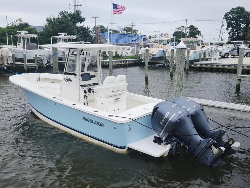 Slide: The Image of 2021 Regulator 25 boat docked with twin Yamaha engines, American flag in background. - 3