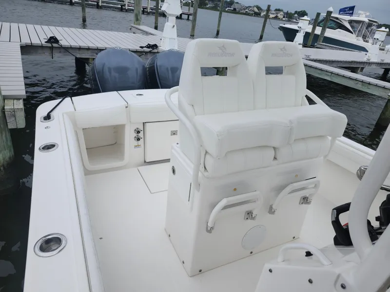 Slide: The Image of 2021 Regulator 25 boat interior with dual seats and twin engines at dock. - 5