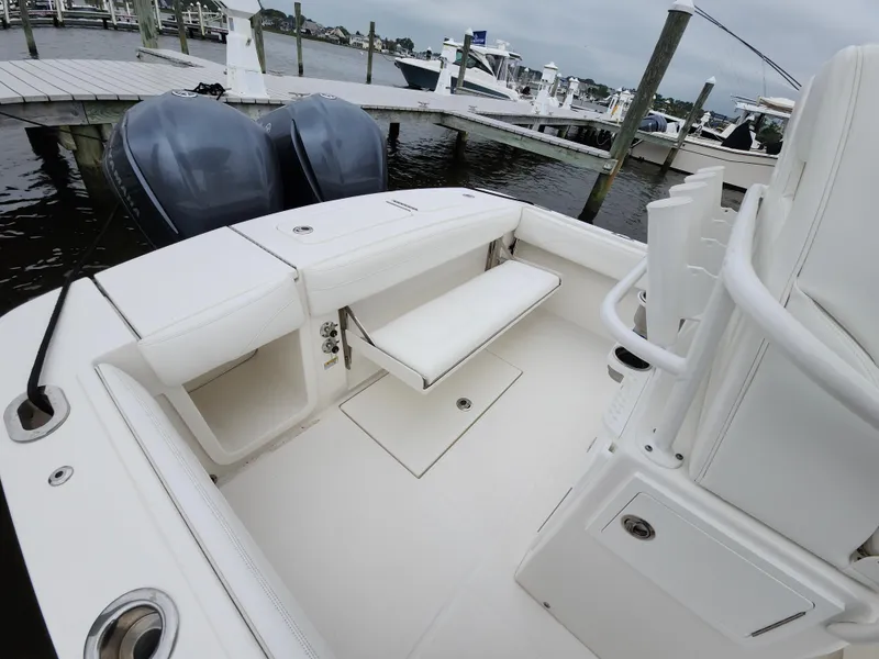 Slide: The Image of 2021 Regulator 25 boat interior with seating and twin engines at a marina. - 6