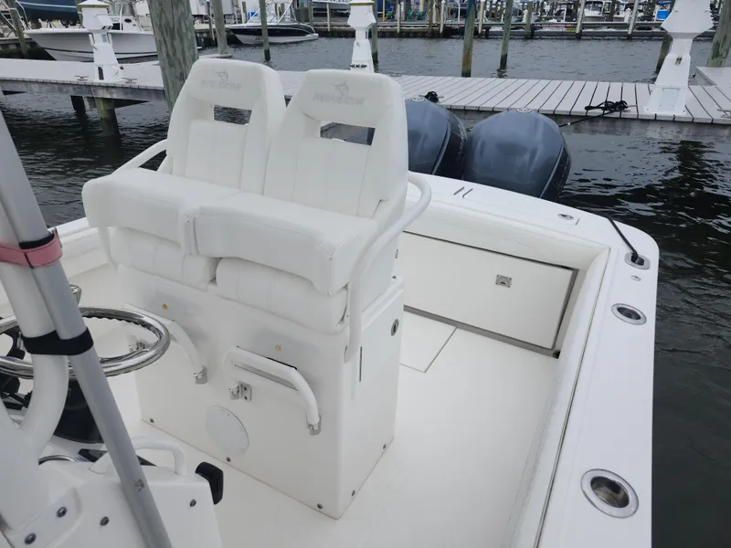 Slide: The Image of 2021 Regulator 25 boat interior with dual seats and twin engines at a marina. - 7