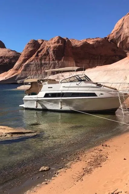 Slide: The Image of 1986 Carver Mariner 32x14.3 yacht docked by rocky shoreline under clear blue sky. - 13