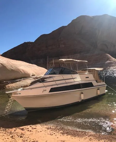 Slide: The Image of 1986 Carver Mariner 32x14.3 boat docked on a sunny, rocky shoreline. - 15