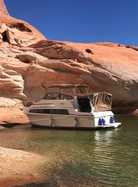 Slide: The Image of 1986 Carver Mariner 32x14.3 boat anchored near red rock formations under clear blue sky. - 16
