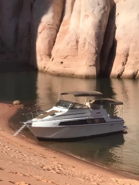 Slide: The Image of 1986 Carver Mariner 32x14.3 boat anchored by rocky shoreline. - 3