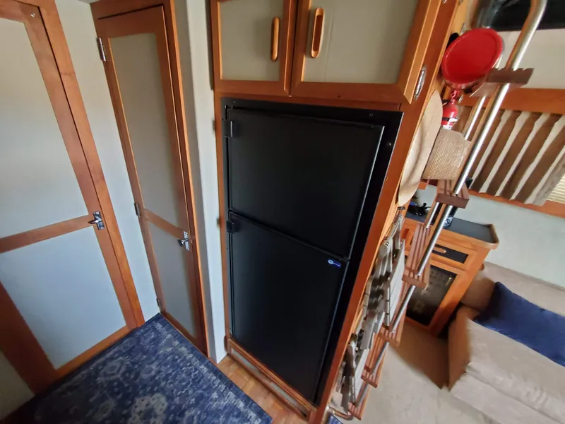 Slide: The Image of Interior of 1986 Carver Mariner 32x14.3 with black fridge, wooden cabinets, and blue rug. - 44