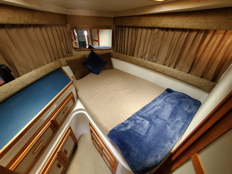Slide: The Image of Cozy cabin interior of 1986 Carver Mariner 32x14.3 with bed, blue blanket, and storage. - 45