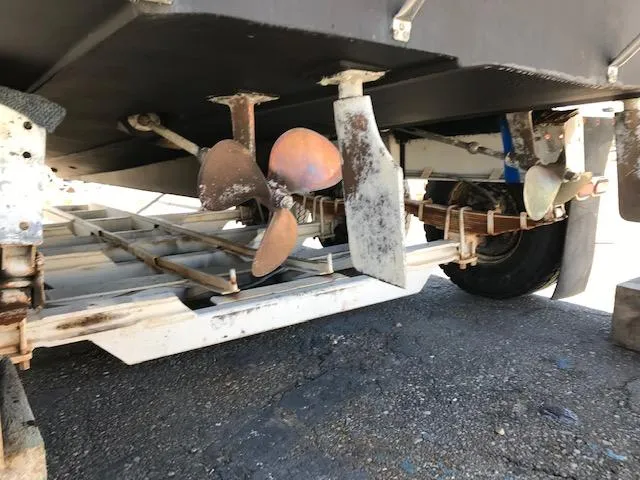 Slide: The Image of 1986 Carver Mariner 32x14.3 boat propellers and rudders on trailer, showing wear and rust. - 7