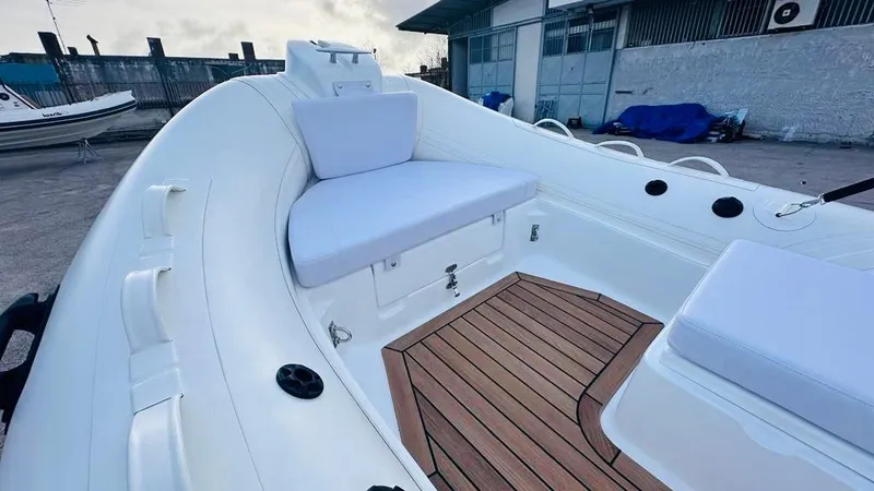 Slide: The Image of 2024 Aqvaboats LUXRIB 14 with white seating and wooden deck, docked at a marina. - 6