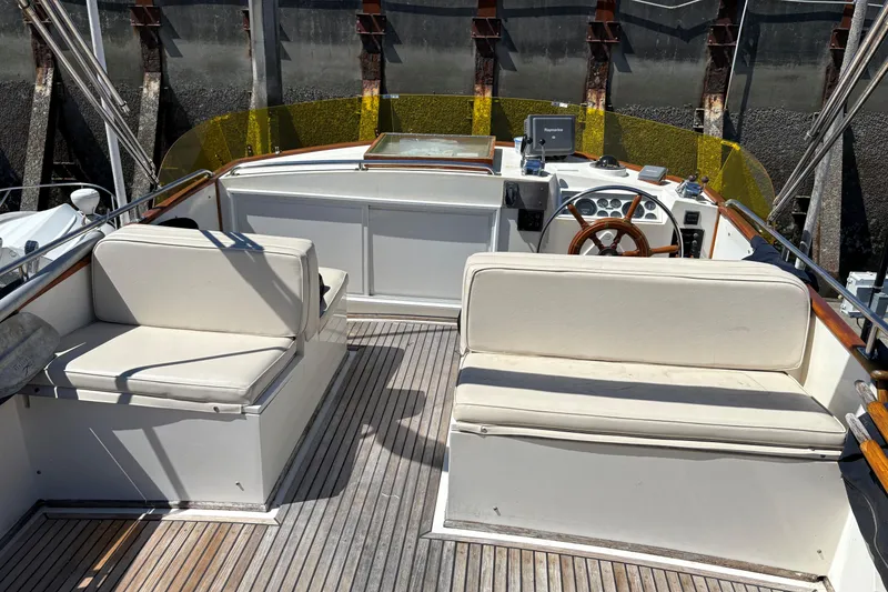 Slide: The Image of 1990 Grand Banks Classic boat interior with wooden deck and cushioned seating. - 2