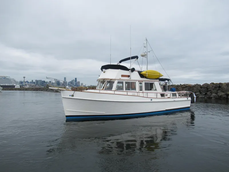 The Image of 1990 Grand Banks Classic boat on calm water with city skyline in background. - 0