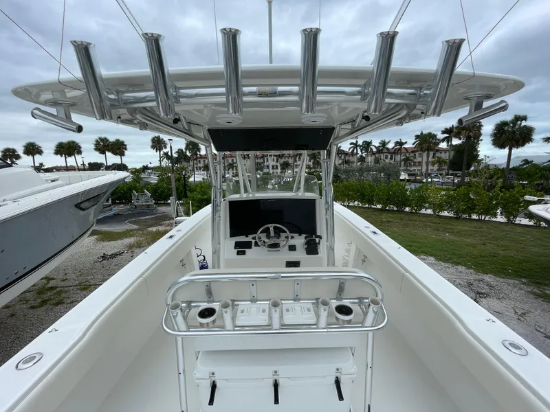 Slide: The Image of 2000 Venture 34 Tournament boat with center console and rod holders, docked near palm trees. - 14