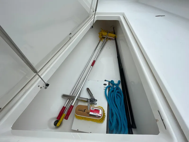 Slide: The Image of Storage compartment of 2000 Venture 34 Tournament boat with cleaning tools and blue rope. - 27