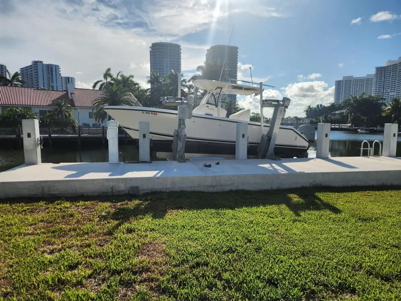 Slide: The Image of 2013 Pursuit C 260 Center Console boat docked near waterfront buildings under a sunny sky. - 1