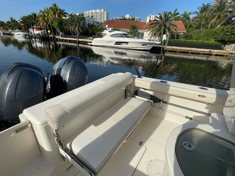 Slide: The Image of 2013 Pursuit C 260 Center Console boat with dual engines, docked near palm trees and waterfront homes. - 11
