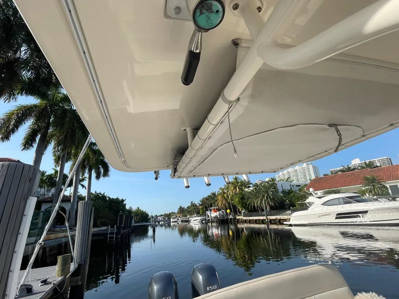 Slide: The Image of 2013 Pursuit C 260 Center Console boat docked by a scenic waterfront with palm trees. - 16