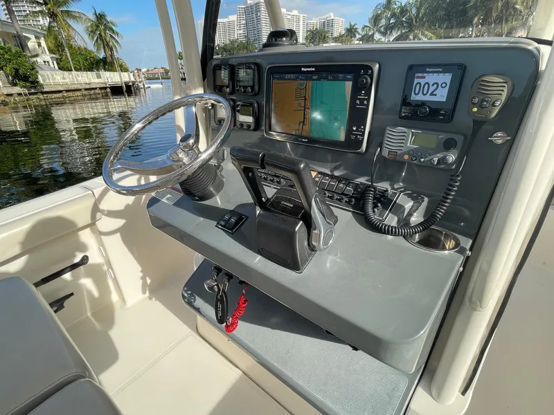 Slide: The Image of 2013 Pursuit C 260 Center Console boat dashboard with navigation equipment and steering wheel. - 18