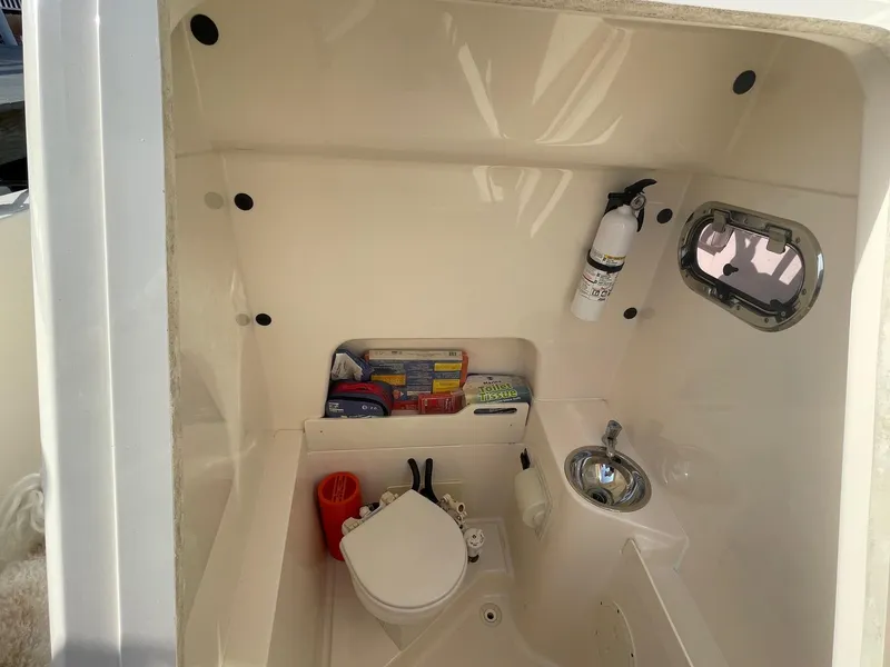 Slide: The Image of 2013 Pursuit C 260 Center Console boat interior with toilet, sink, and storage. - 8