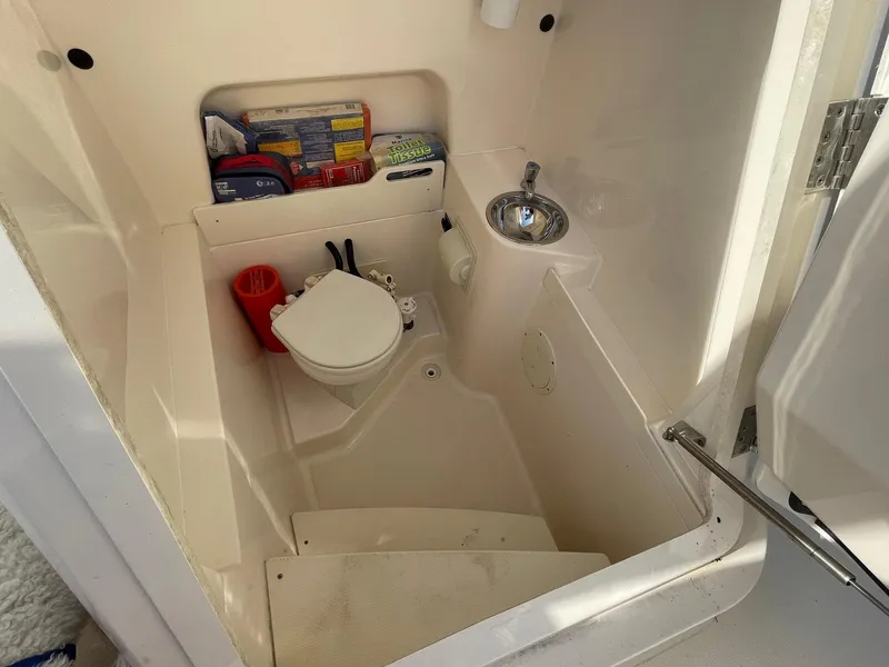 Slide: The Image of 2013 Pursuit C 260 Center Console boat interior with toilet and sink. - 9