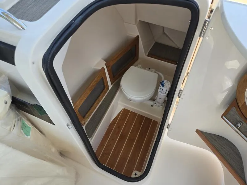 Slide: The Image of 2026 Grady-White Freedom 235 boat interior with compact bathroom and wooden accents. - 14