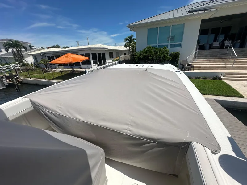 Slide: The Image of 2024 World Cat 280ccx boat with cover, docked near waterfront homes. - 17