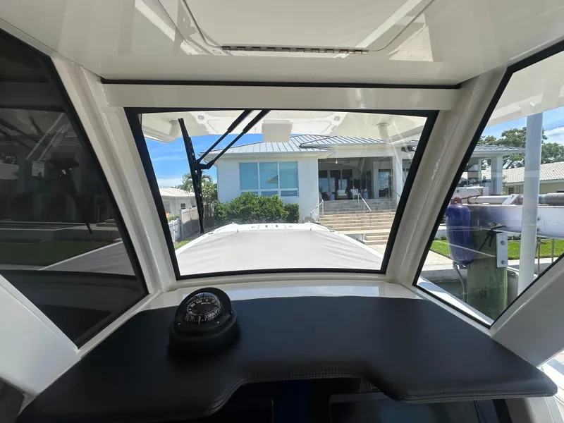 Slide: The Image of 2024 World Cat 280ccx boat interior with compass, docked near modern building. - 32