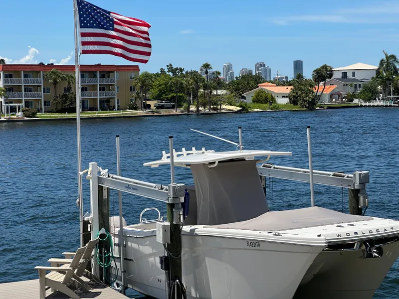 Slide: The Image of 2024 World Cat 280ccx boat docked by waterfront with American flag and city skyline. - 5