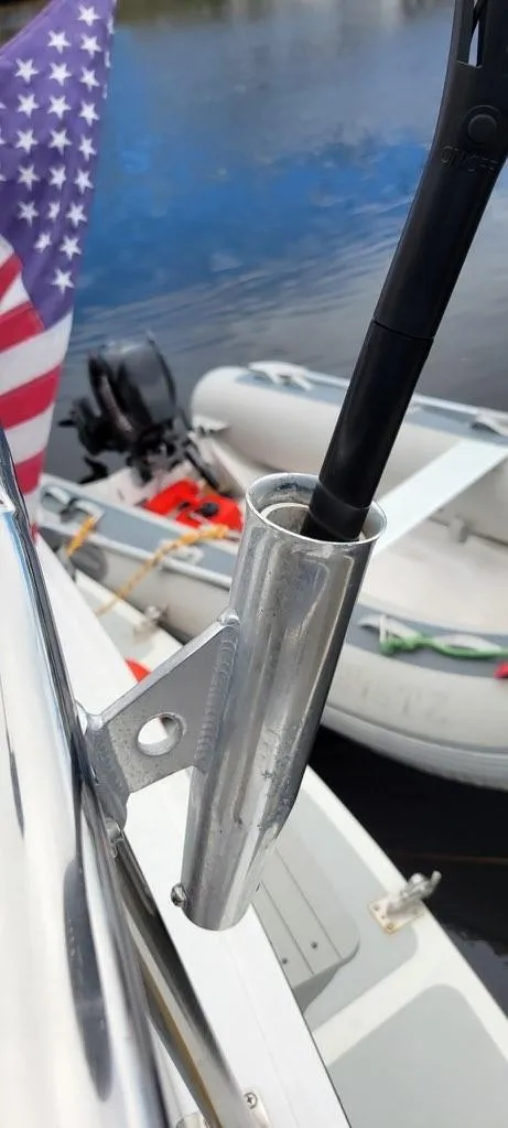 Slide: The Image of Flagpole holder on a 2001 Monk 36 boat, with American flag and dinghy in background. - 19
