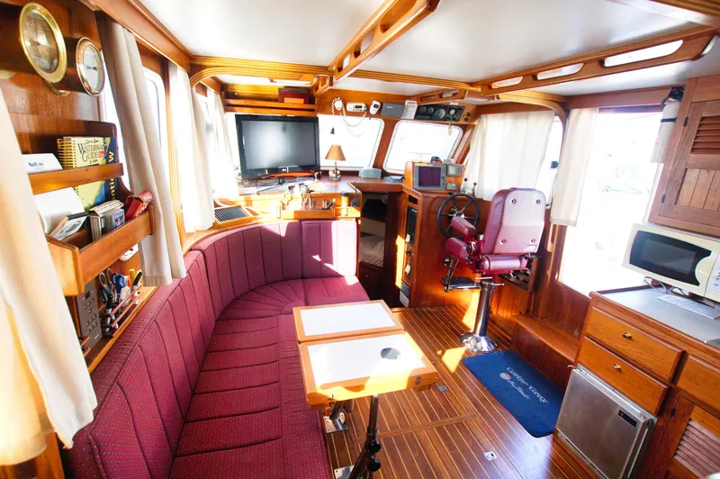 Slide: The Image of Interior of 2001 Monk 36 boat, featuring cozy seating, navigation area, and wooden cabinetry. - 26