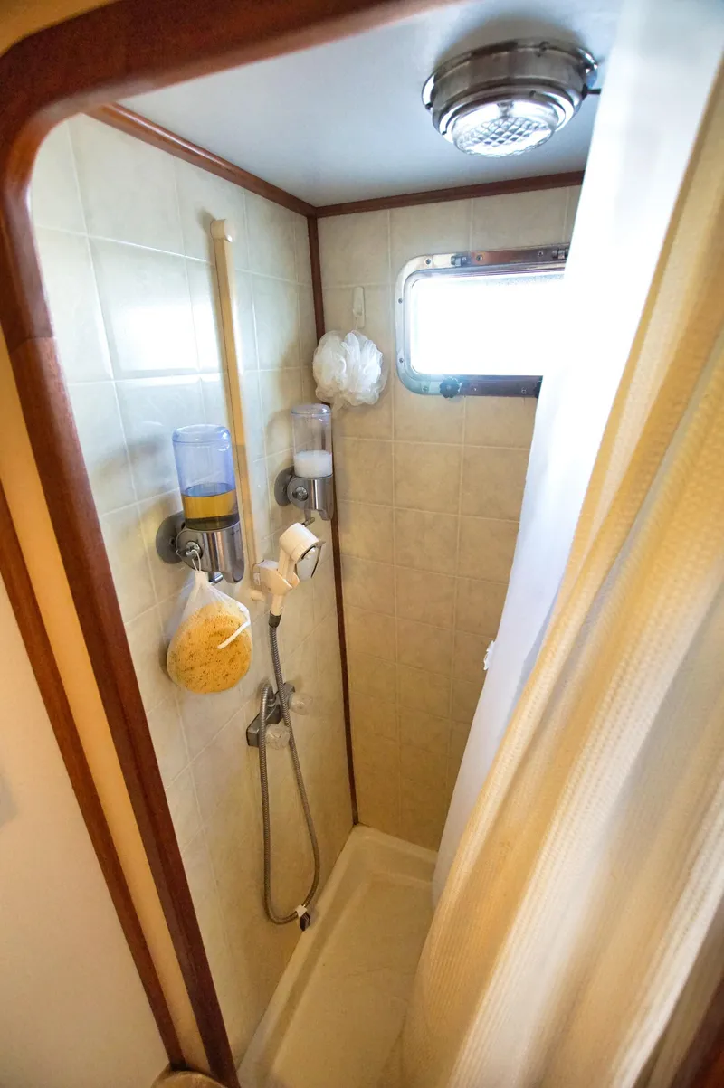 Slide: The Image of Compact boat shower with beige tiles, wooden trim, and a small window on a 2001 Monk 36. - 38