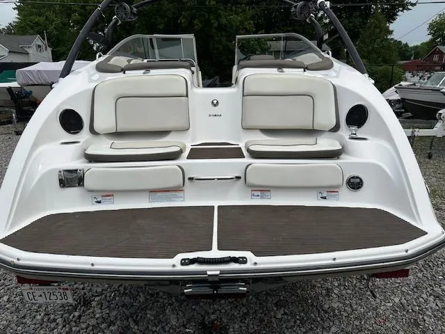 Slide: The Image of 2013 Yamaha Boats 242 Limited S, rear view, white and beige seating, on gravel surface. - 13
