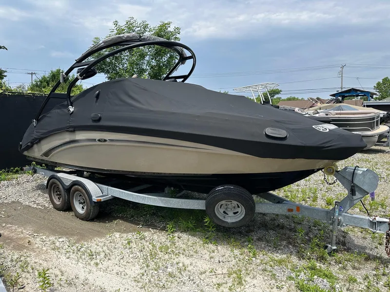 Slide: The Image of 2013 Yamaha Boats 242 Limited S covered on trailer, parked outdoors. - 2