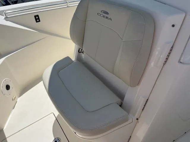 Slide: The Image of 2019 Cobia 320 Center Console boat seat with logo, featuring sleek white upholstery. - 19