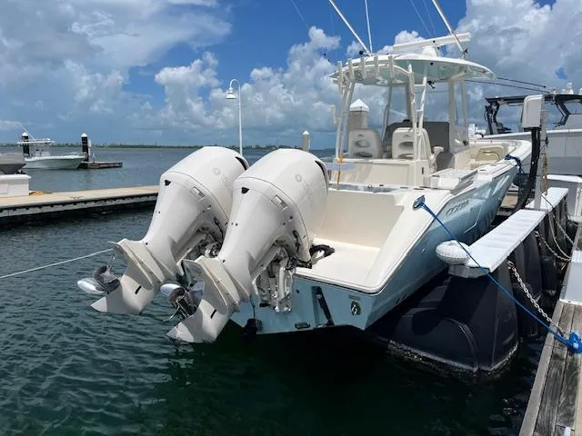 Slide: The Image of 2019 Cobia 320 Center Console boat docked with twin outboard engines. - 28