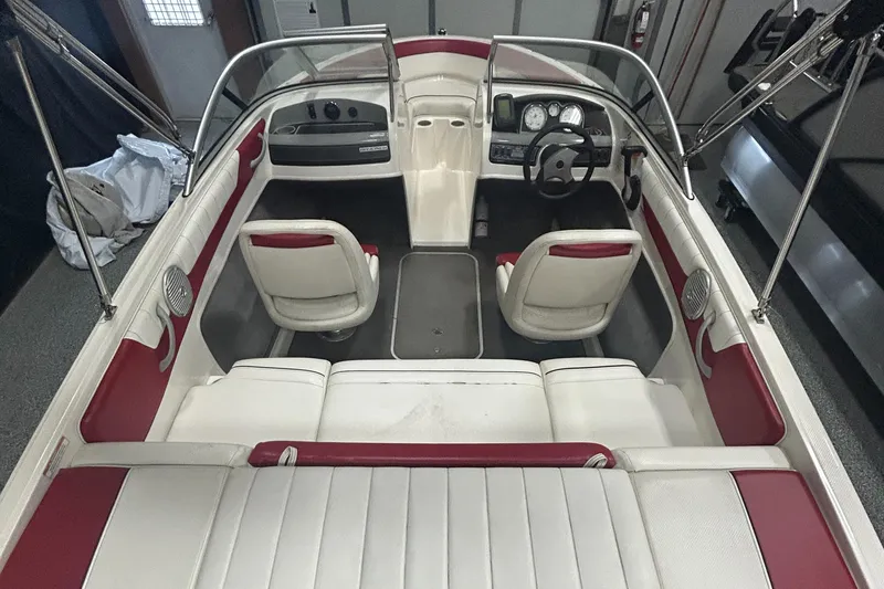 Slide: The Image of 2013 Bayliner 185 Bowrider interior with white and red seating, steering wheel, and dashboard. - 10